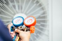 Technician using HVAC gauges to check system performance, ensuring optimal operation and efficiency.